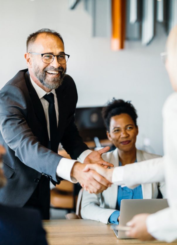 Smiling business professionals celebrating a successful negotiation with a handshake, emphasizing positivity and accomplishment in the workplace