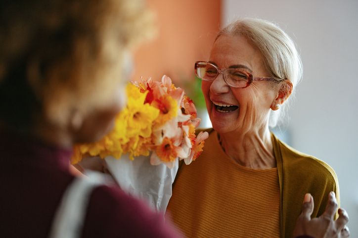 Senior woman happily receiving flowers