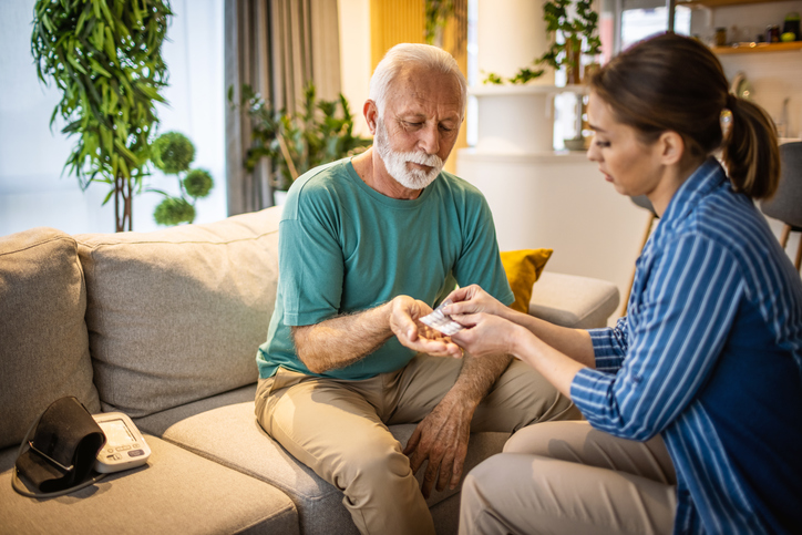 Caregiver giving senior man medication