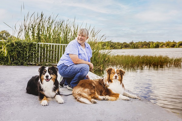 woman kneels on patio by Lake Hunter with her two border collie dogs