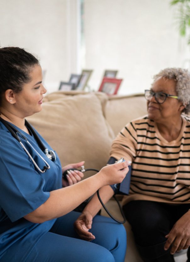 Healthcare worker taking blood pressure of senior woman at home