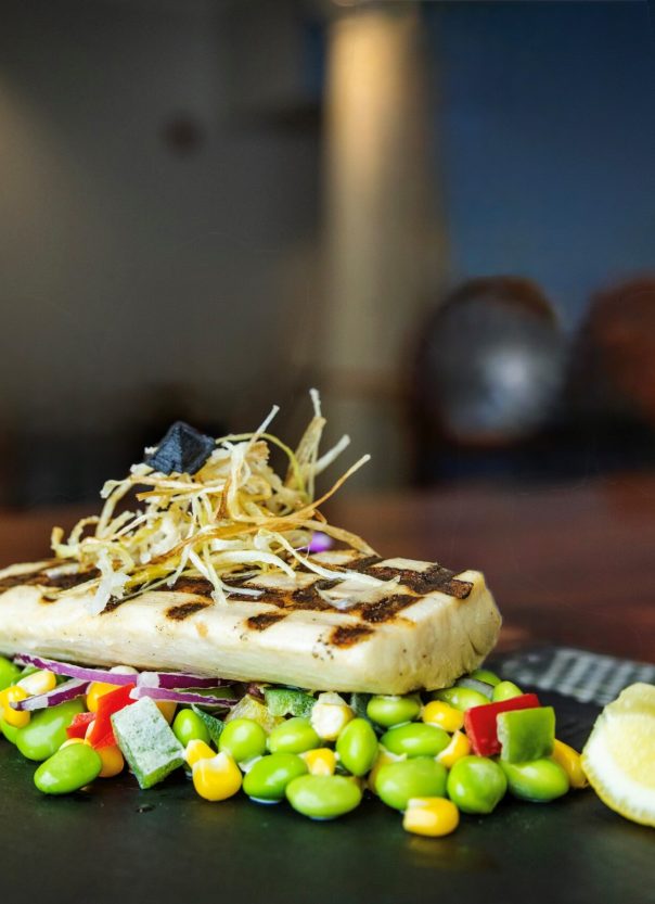 grilled steak fish sits atop bed of fresh succotash salad