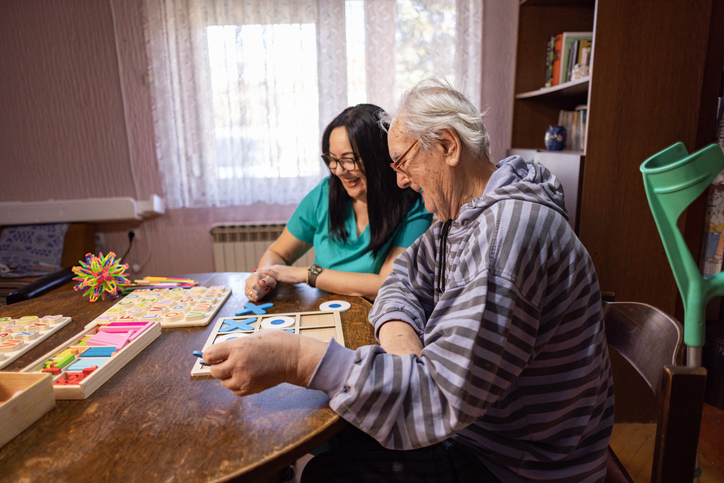Caregiver playing tik tac toe with senior man