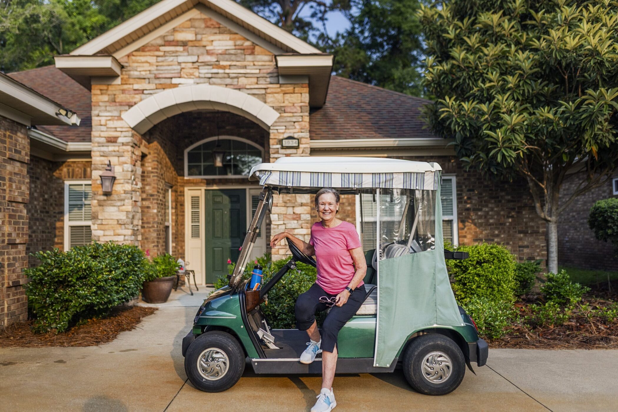 senior posing by golf cart