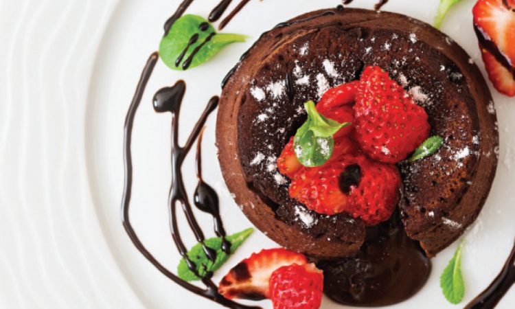 Fresh chocolate torte on a white plate from above