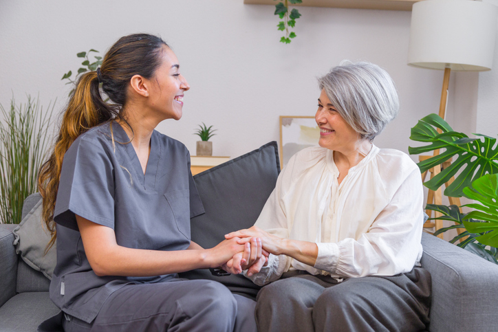 Young nurse holding hands of a senior woman, providing care and support