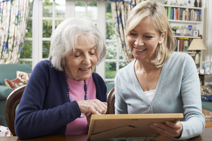 Senior Woman Looks At Photo Frame With Loved One