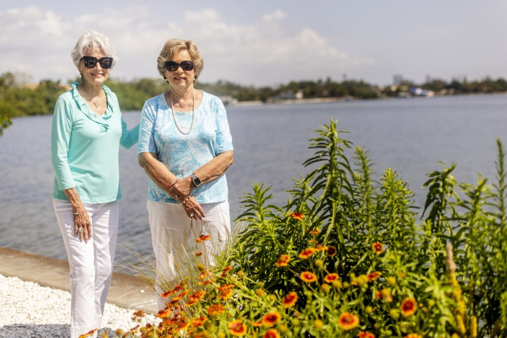 two seniors standing outside, smiling