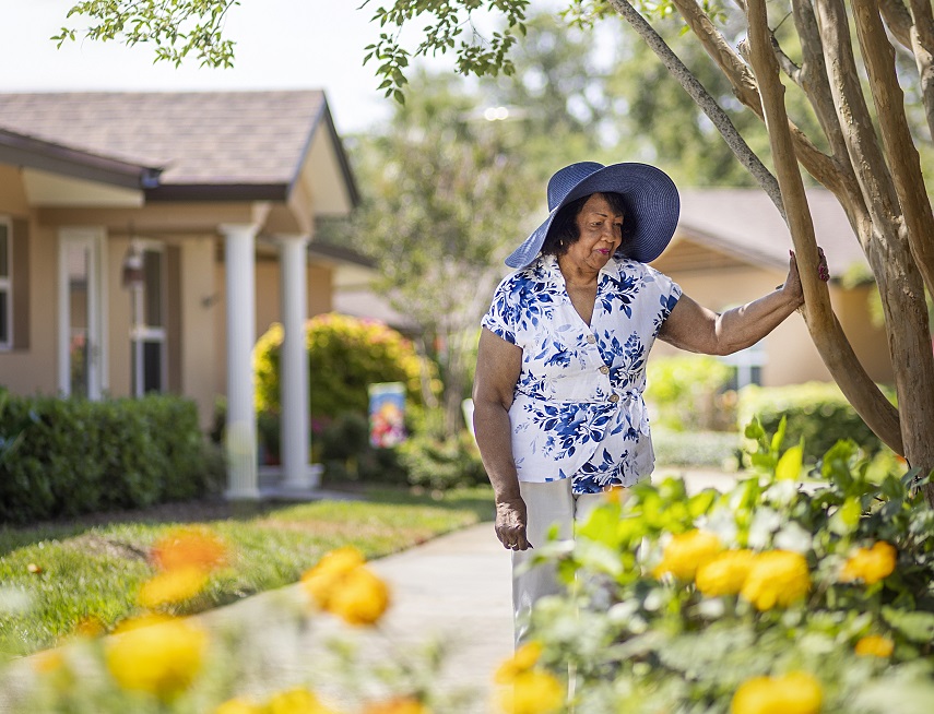 woman stands near garden looking into flowers