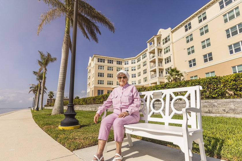 woman in pink jogging suit sits on bench overlooking Little Bayou in St. Petersburg