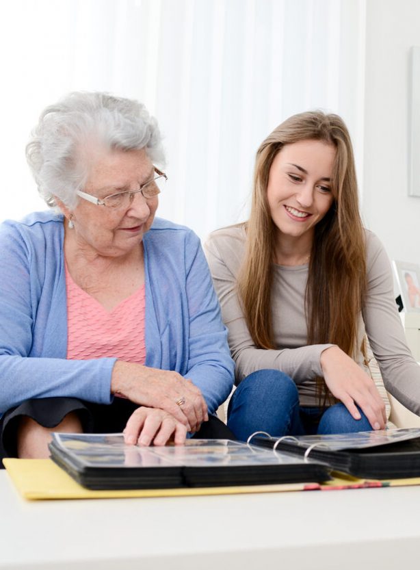 old senior woman with young granddaughter at home looking souvenir