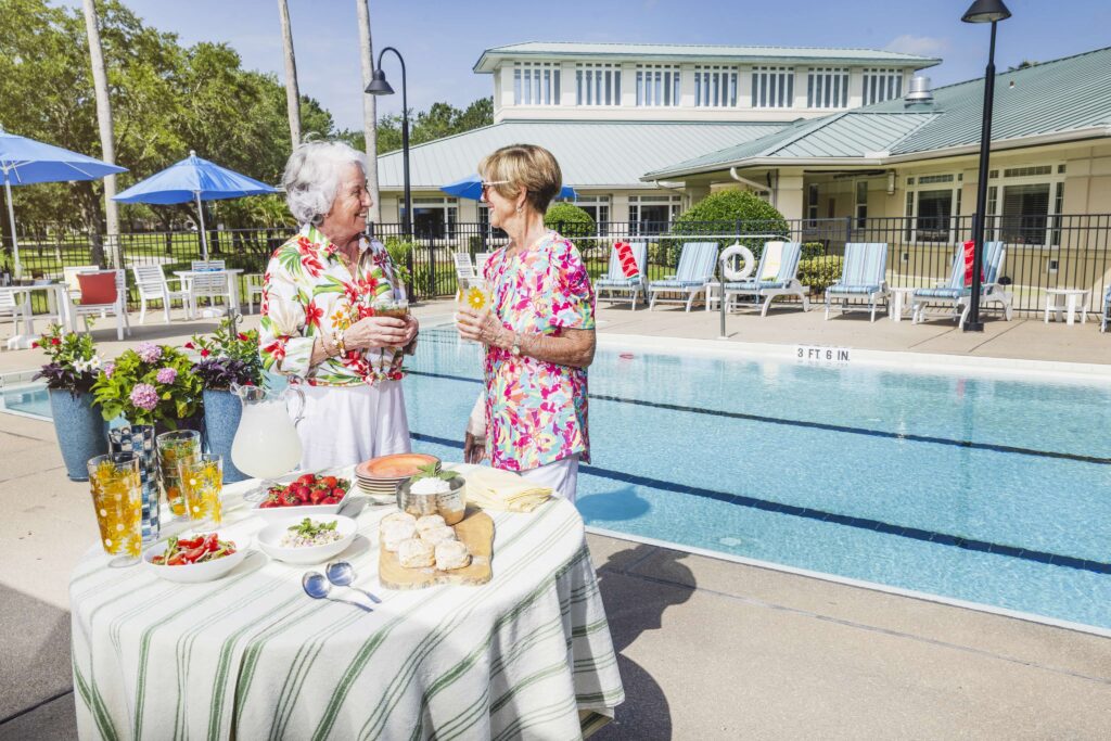 Female senior friends sharing a drink by the pool
