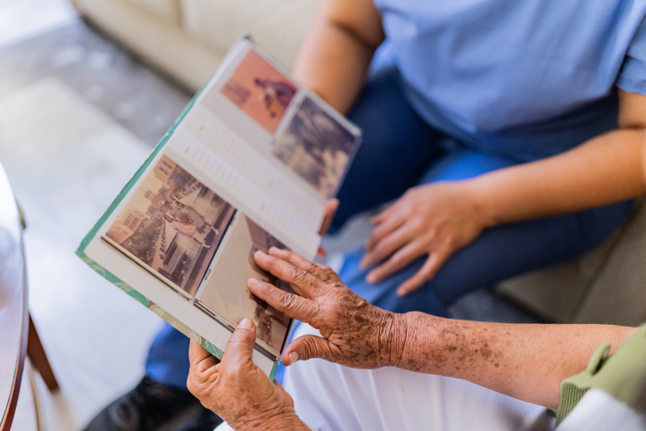 Close-up of senior woman and home caregiver looking photo album
