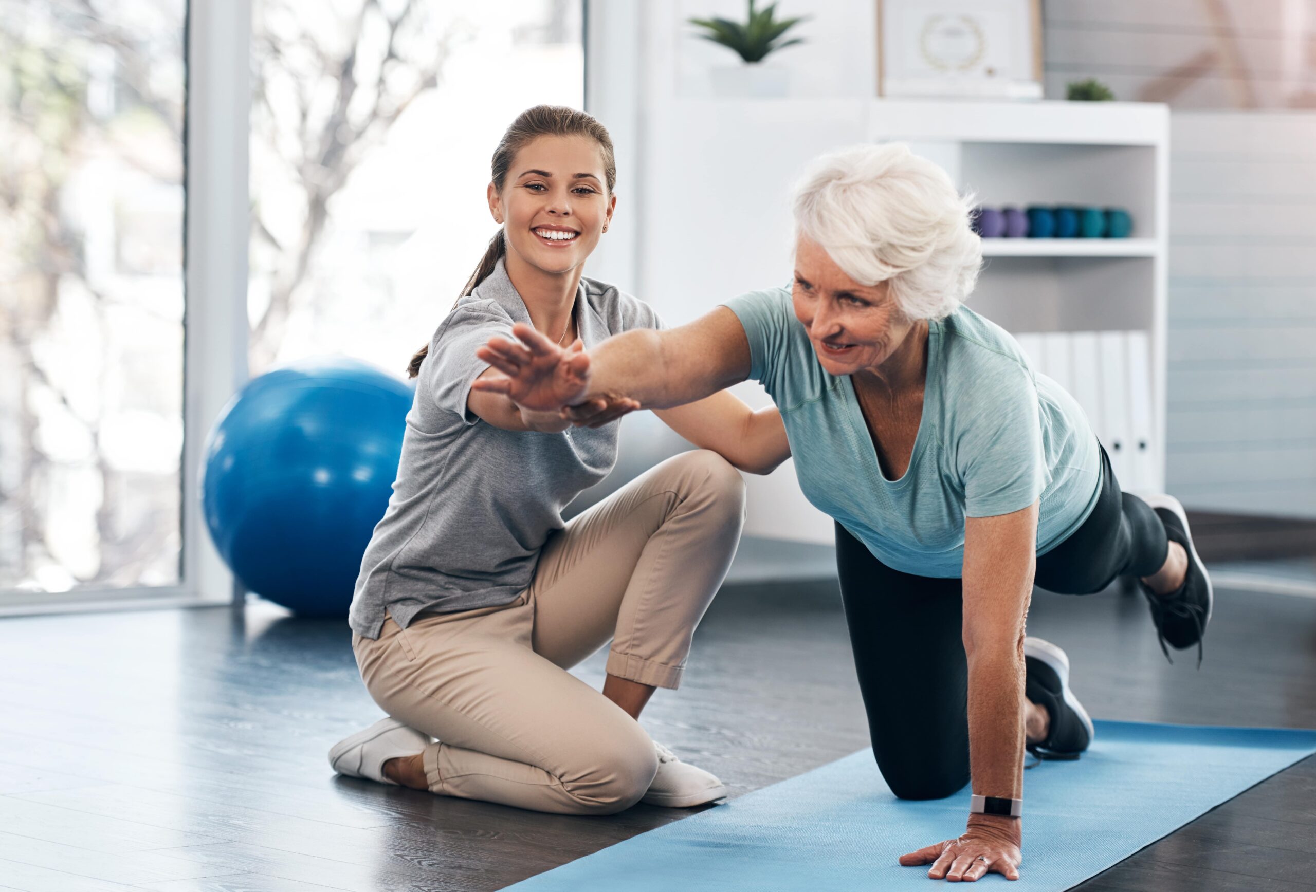 caregiver assisting senior woman through physical therapy