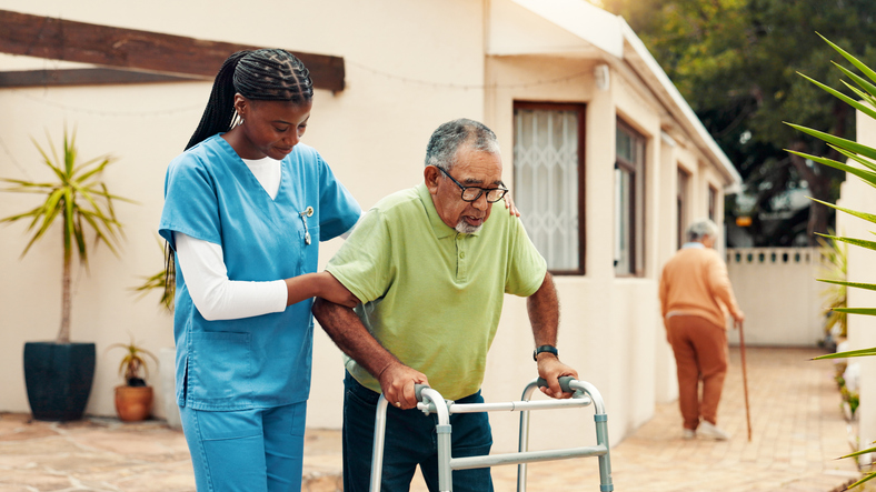 Caregiver helping man walk after surgery