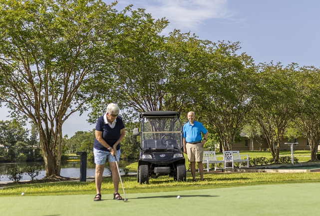 woman lines up shot on putting green