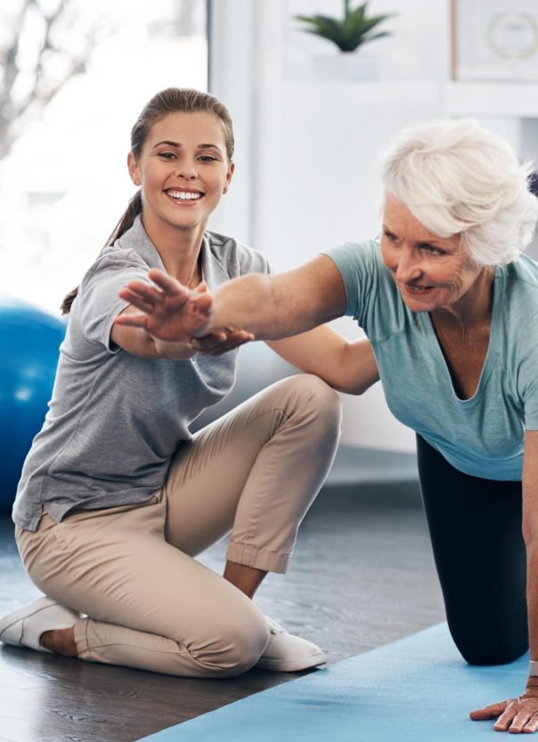 caregiver assisting senior woman through physical therapy