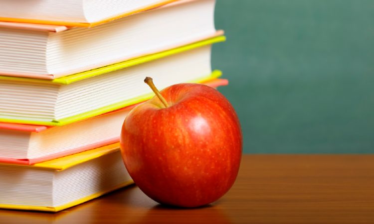 Apple on a desk next to a set of books
