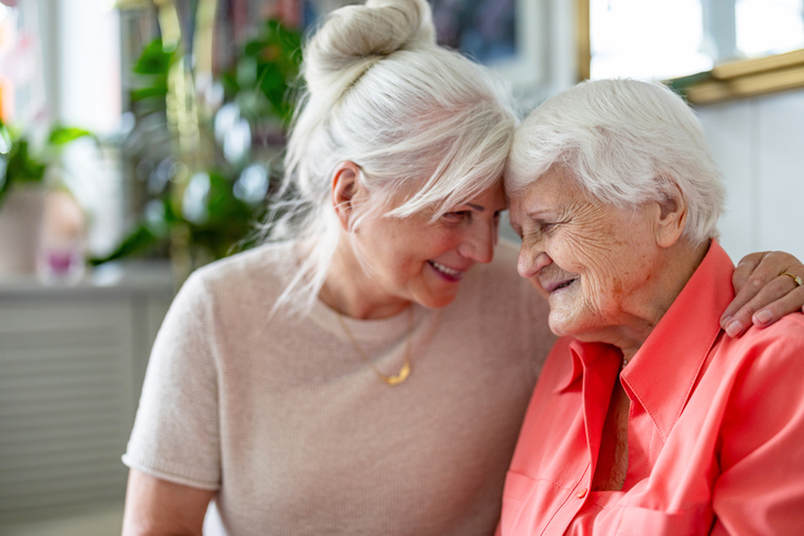 Senior with younger friend sharing a hug and smiles