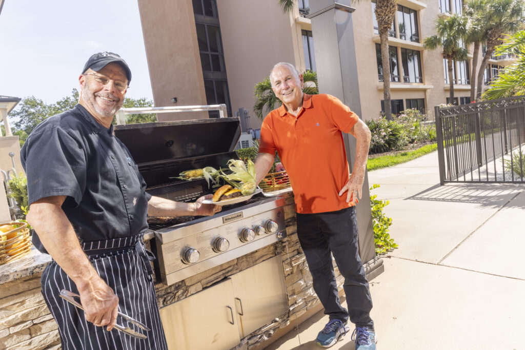 Senior Man Outside by Grill Smiling with Chef