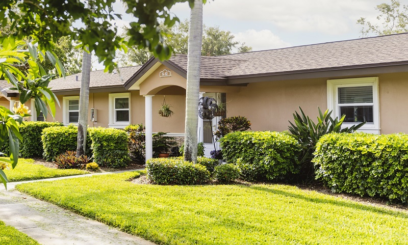 tan stucco villa with covered front porch and palm trees