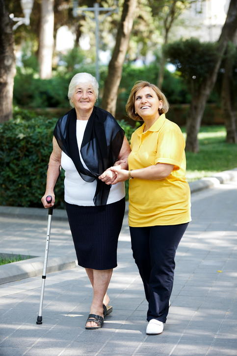 Professional caregiver taking care of senior woman, outdoors.