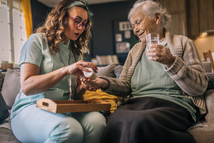 Senior receiving medications from caregiver