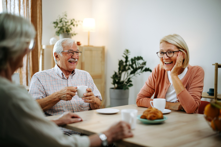 Senior couple having coffee with their mature daughter at home