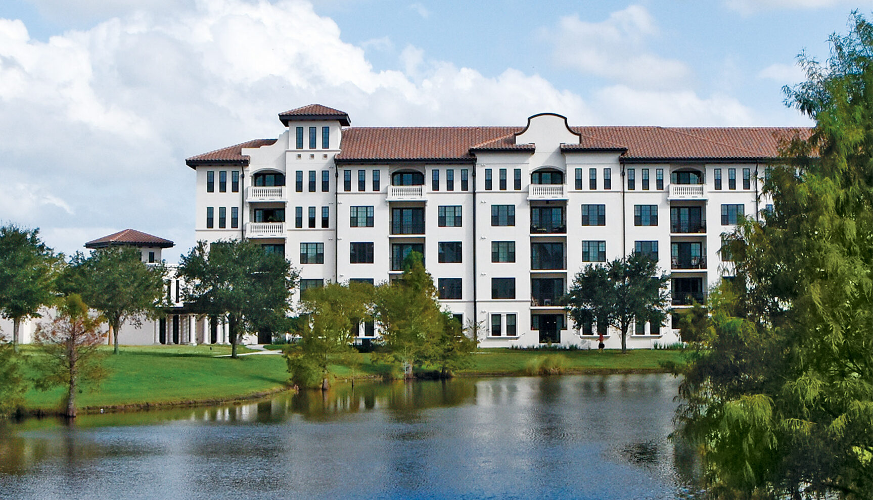 Westminster Baldwin Park spanish colonial style building with lagoon in foreground