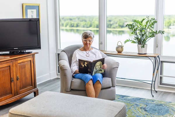 woman sits in living room reading book with Lake Berry in Winter Park in background