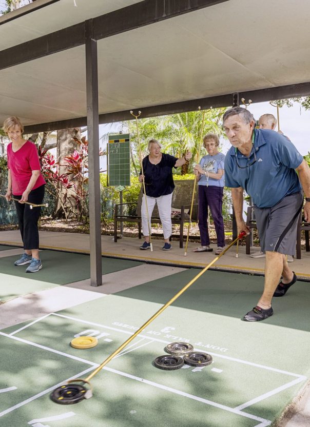 group of residents at Westminster Winter Park play shuffleboard on community court