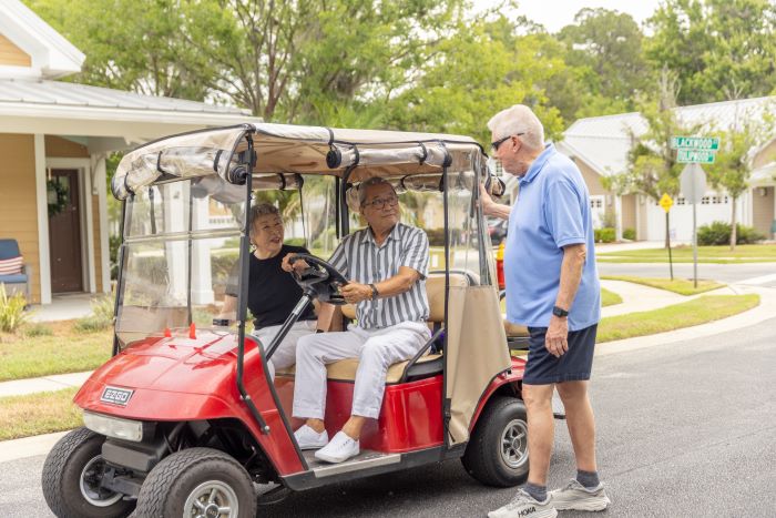 Seniors riding in golf cart greeted by friends