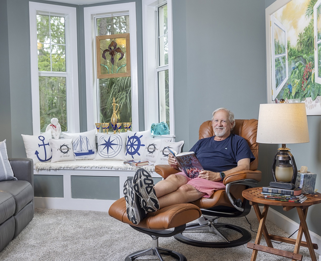 Man sits in modern reading chair with his feet up smiling at camera