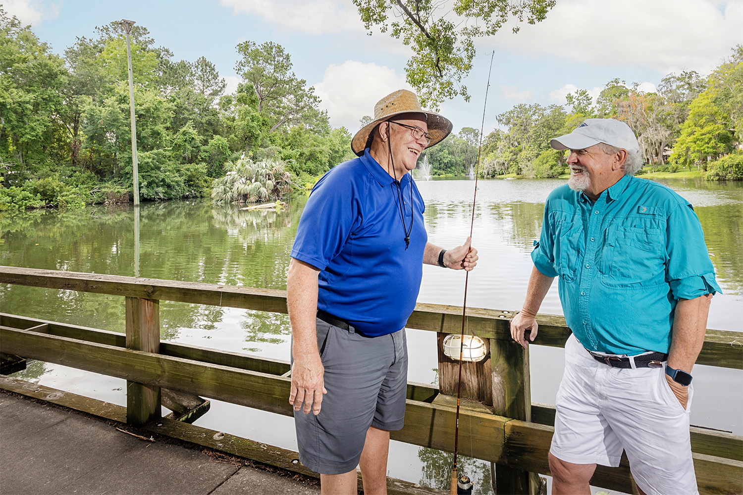 Two men on a walking path with fishing poles smiling