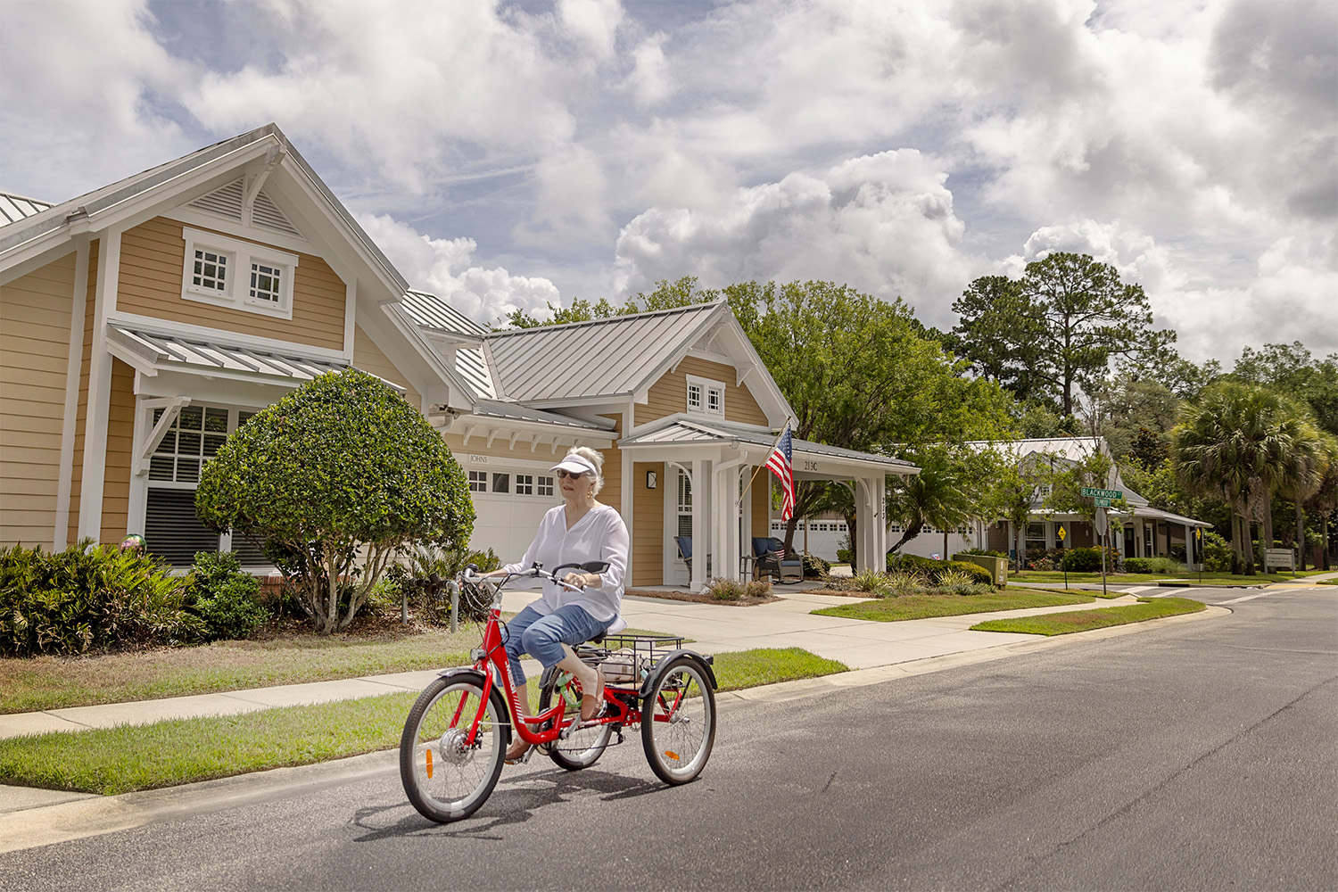 A woman on a tricycle riding past neighborhood cottages