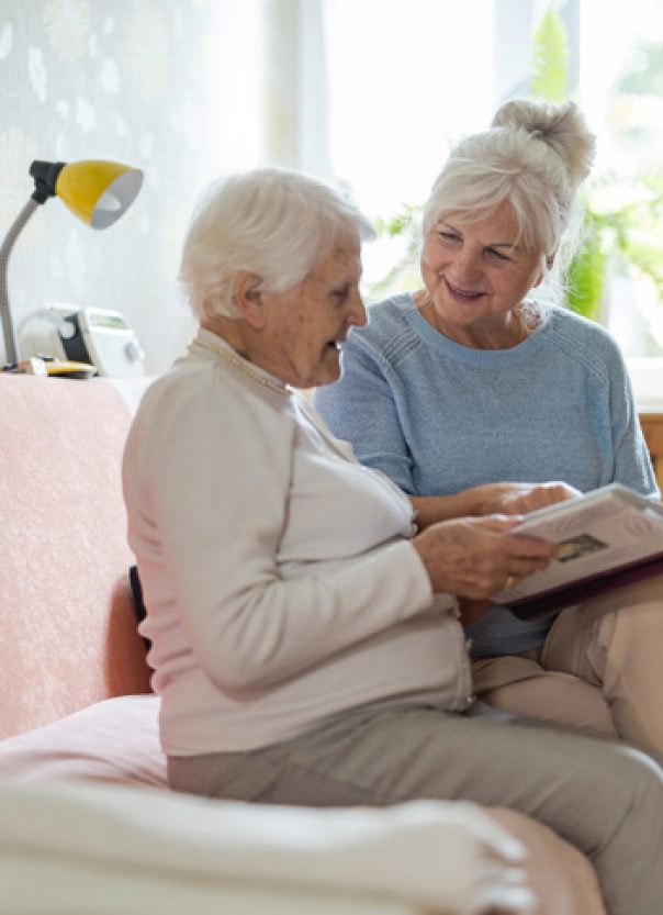 Senior woman and her adult daughter looking at photo album together