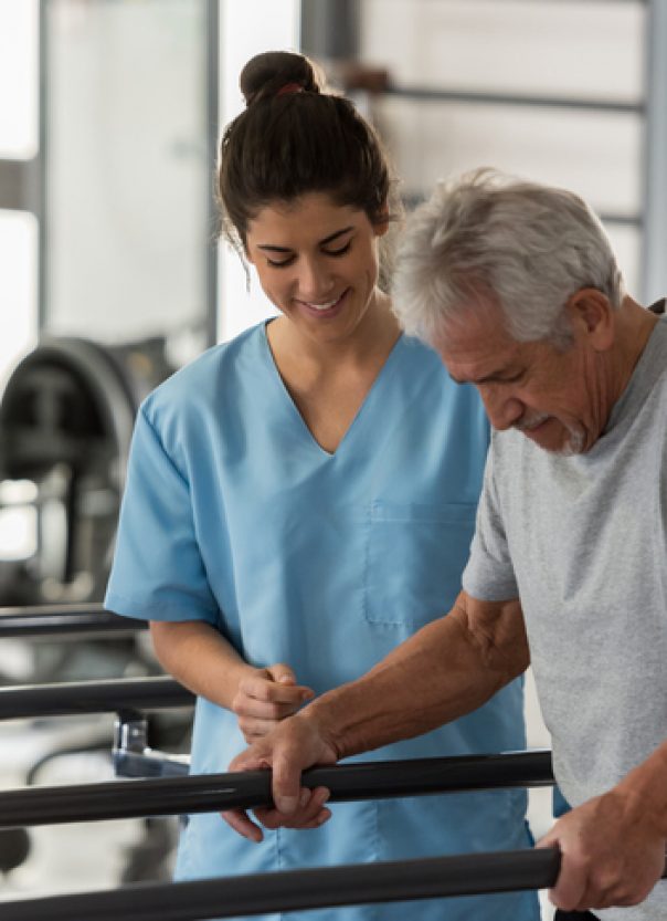 Physiotherapist helping a senior patient while he walks using his hands to support his weight on the bars and therapist looking very happy