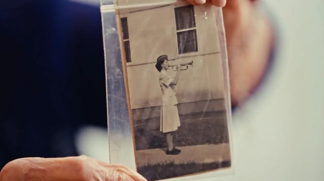 Woman holding old photograph of her playing bugle