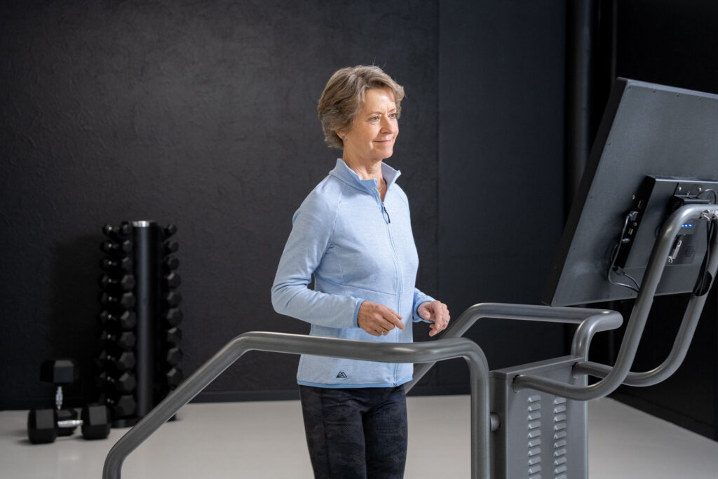 Older adult walking on a treadmill while performing a dual-task exercise to improve balance, mobility, and memory.