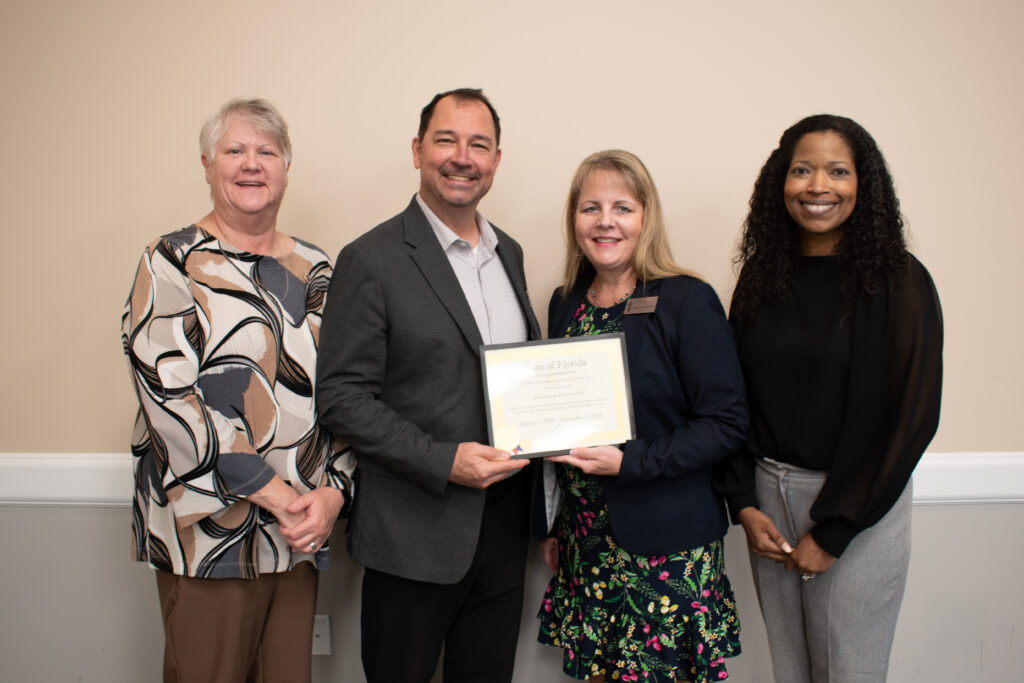 Secretary Shevaun Harris and Deputy Secretary Kimberly Smoak present the Governor’s Gold Seal Award certificate to Executive Director Mark Neimeyer and Health Services Administrator Laure Zulkowski during a celebration at Westminster Baldwin Park.