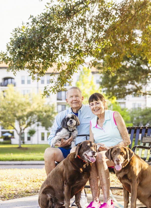Seniors sitting on bench taking picture with their three dogs