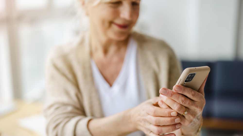 senior woman smiling while looking at smart phone