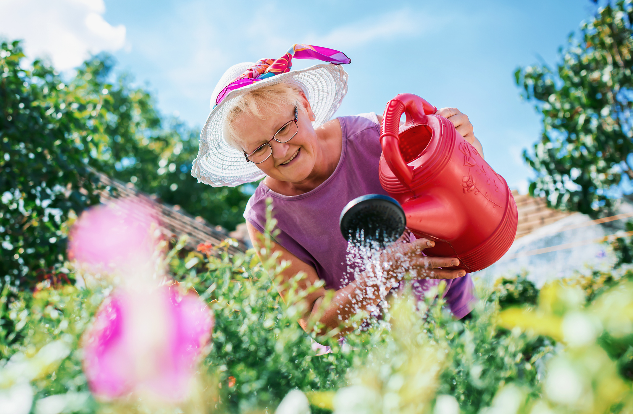 Senior woman watering flowers in a garden