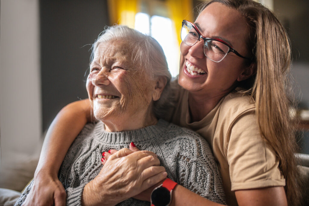Adult daughter hugging and laughing with senior mother