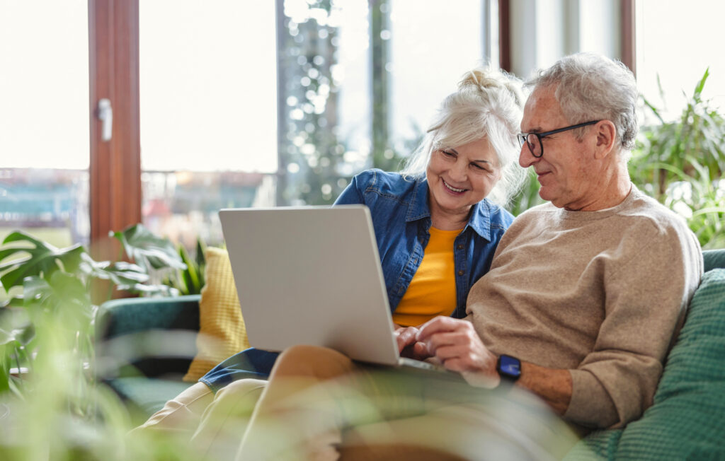 Senior couple using laptop while sitting on couch at home