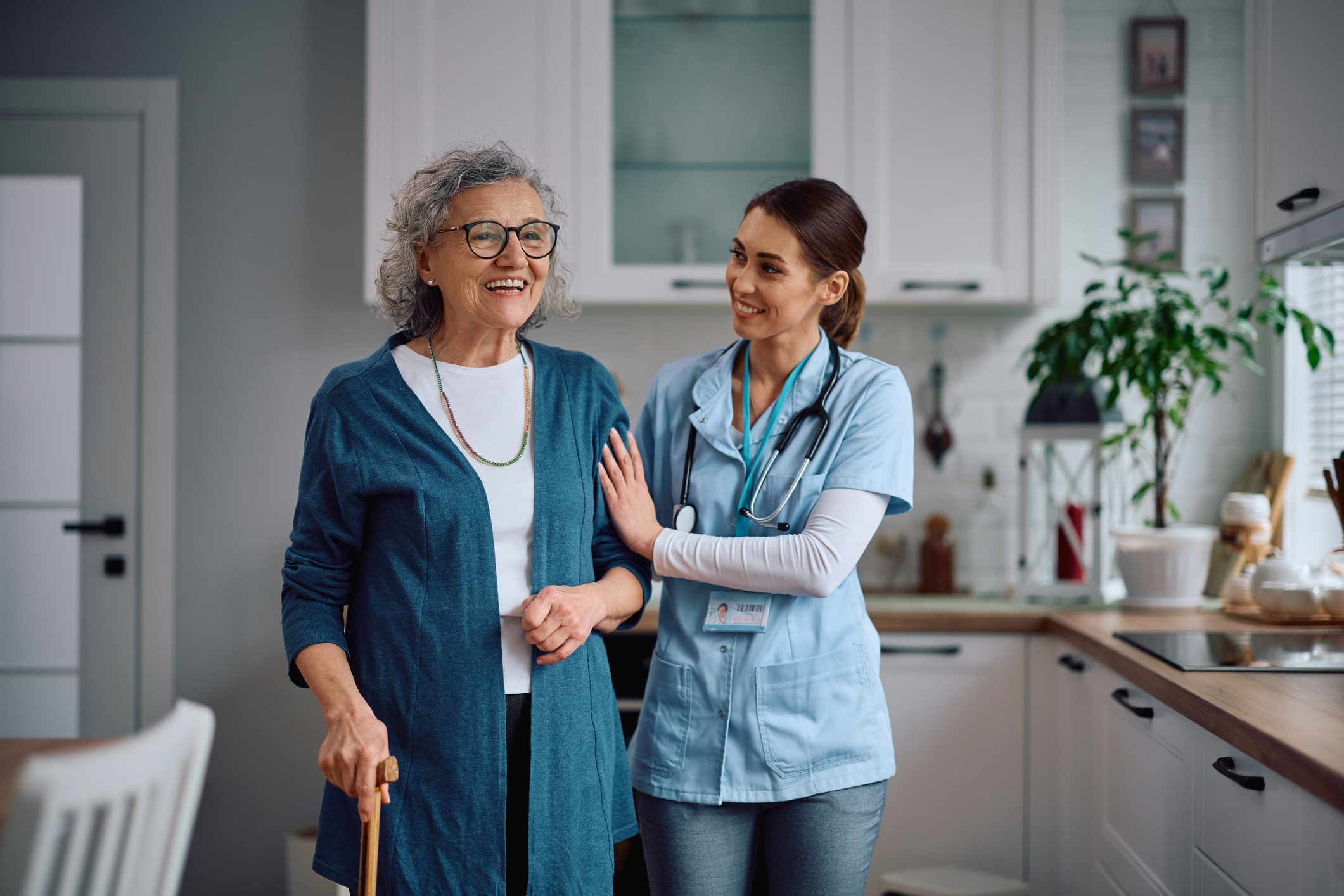 Senior woman walking with help from a caregiver through home care