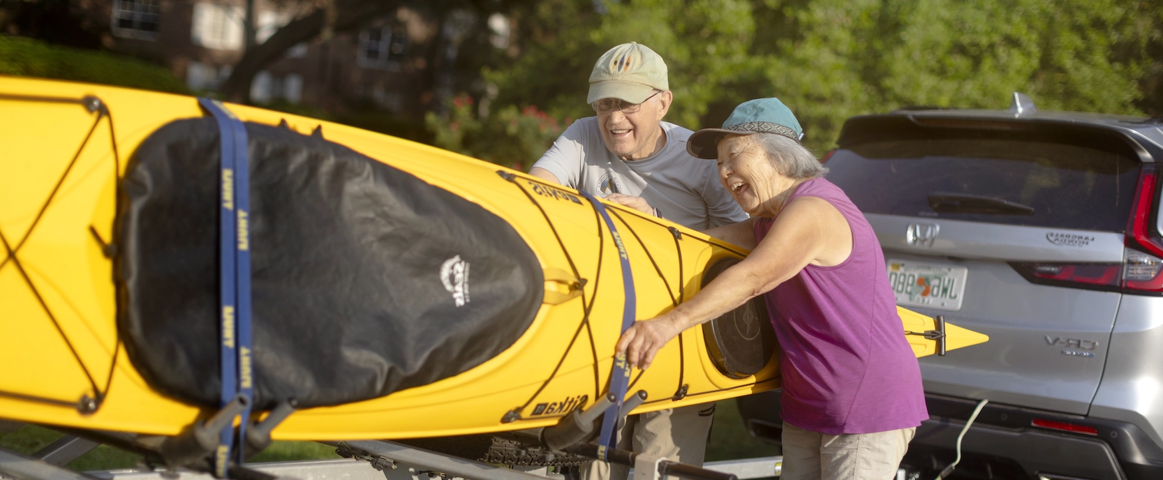 A couple carrying a kayak into a car at Westminster Oaks